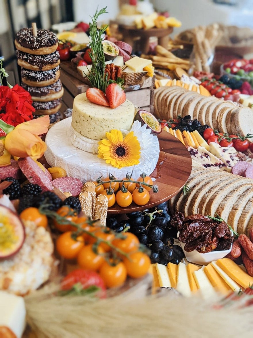 A colourful event buffet with cheeses, savoury bites, fruit and desserts