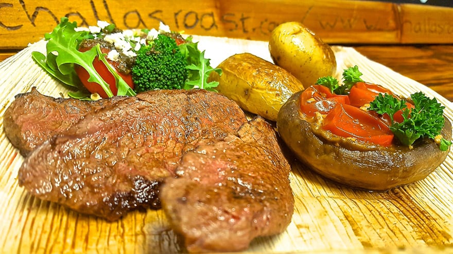 Grilled meat with fresh greens, potato and tomato sides