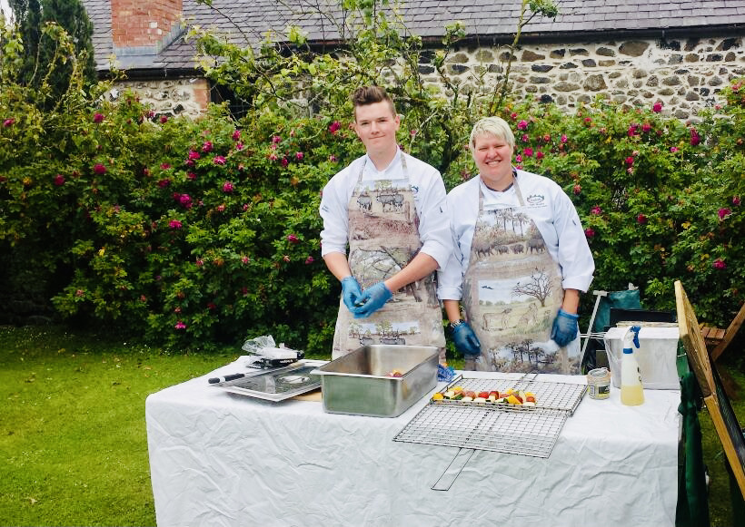 Two cooks preparing food at an outdoor catering event